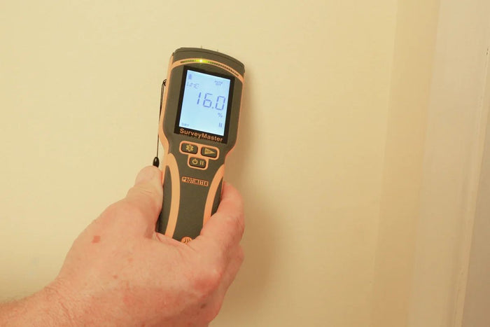 Thorair PROTIMETER SurveyMaster measuring moisture level on a beige wall with digital display