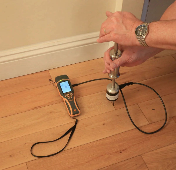 Thorair PROTIMETER device measuring moisture levels in wooden floor planks with handheld sensor